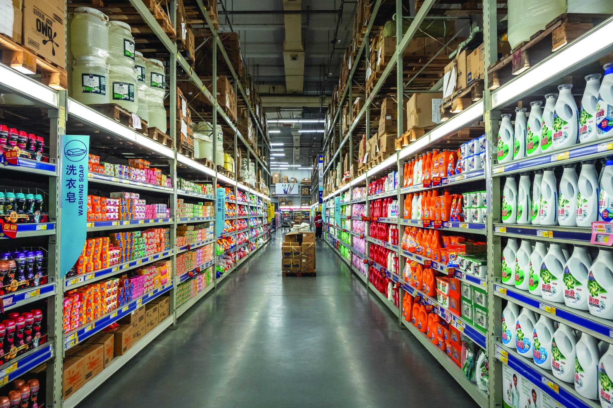Inside a dark store: long aisles of racking stocked with household products