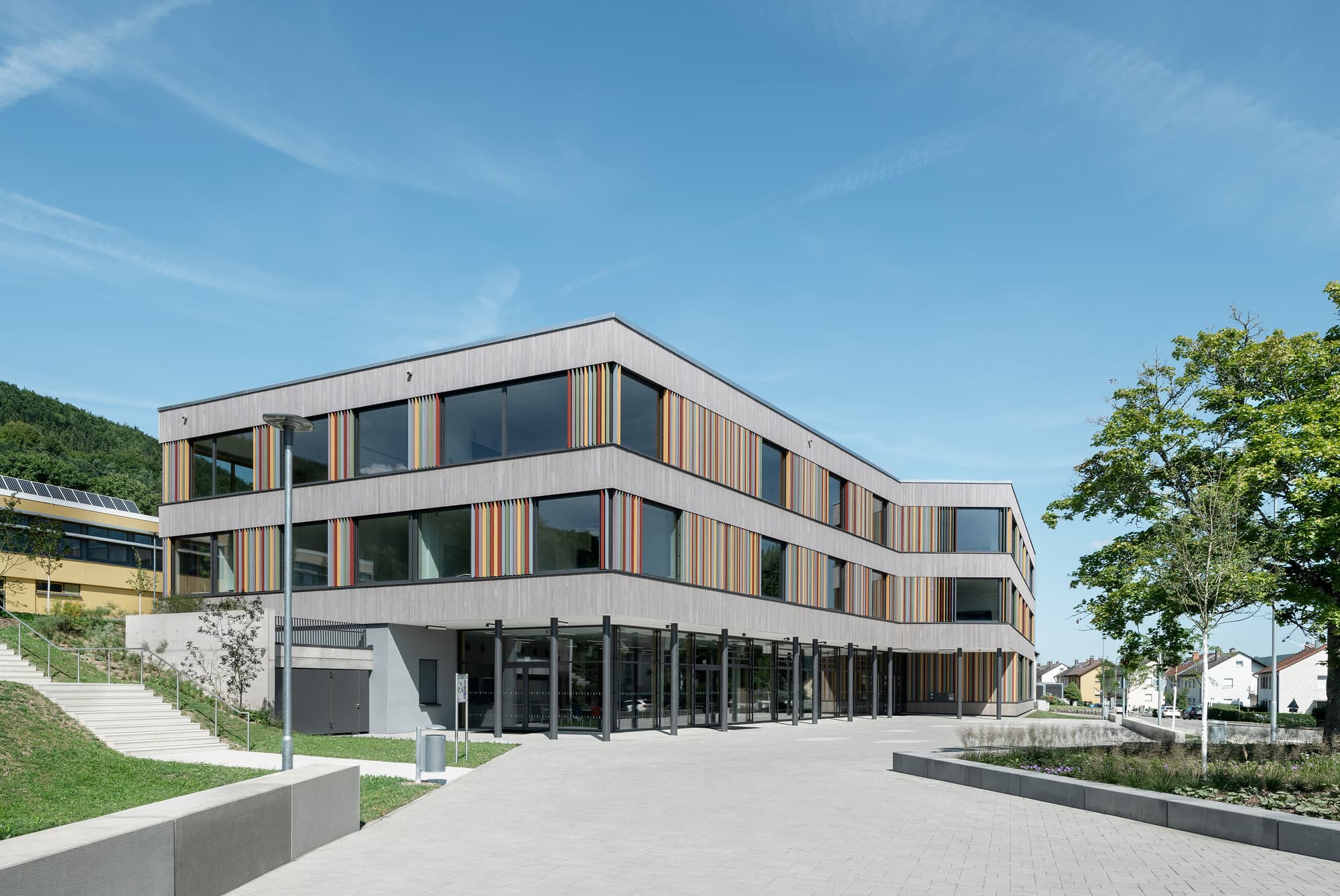 Modern three-storey K-12 school building with a landscaped forecourt